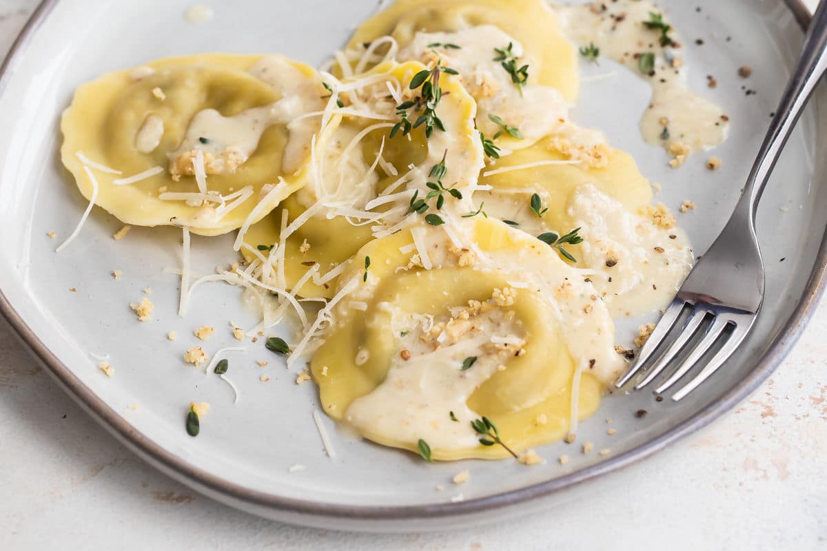 A plate of mushroom ravioli and a glass of white wine.