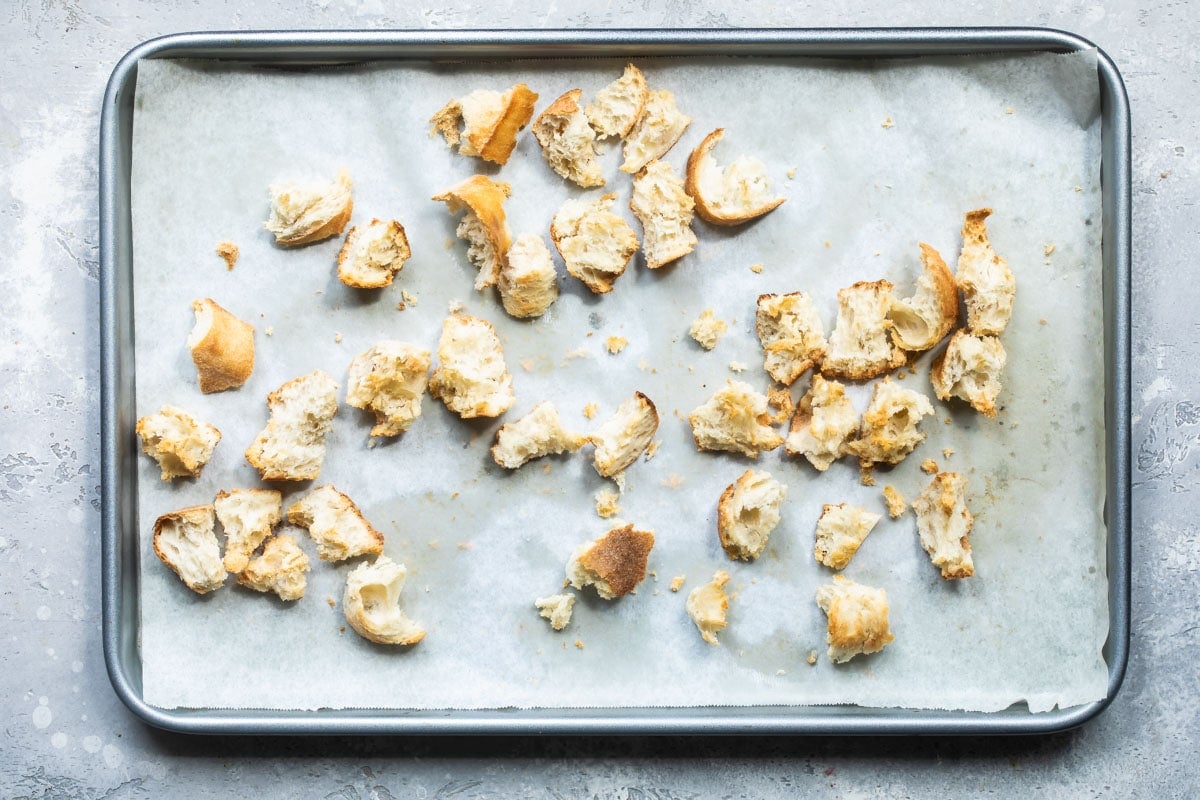 Pieces of bread on a parchment lined baking sheet.