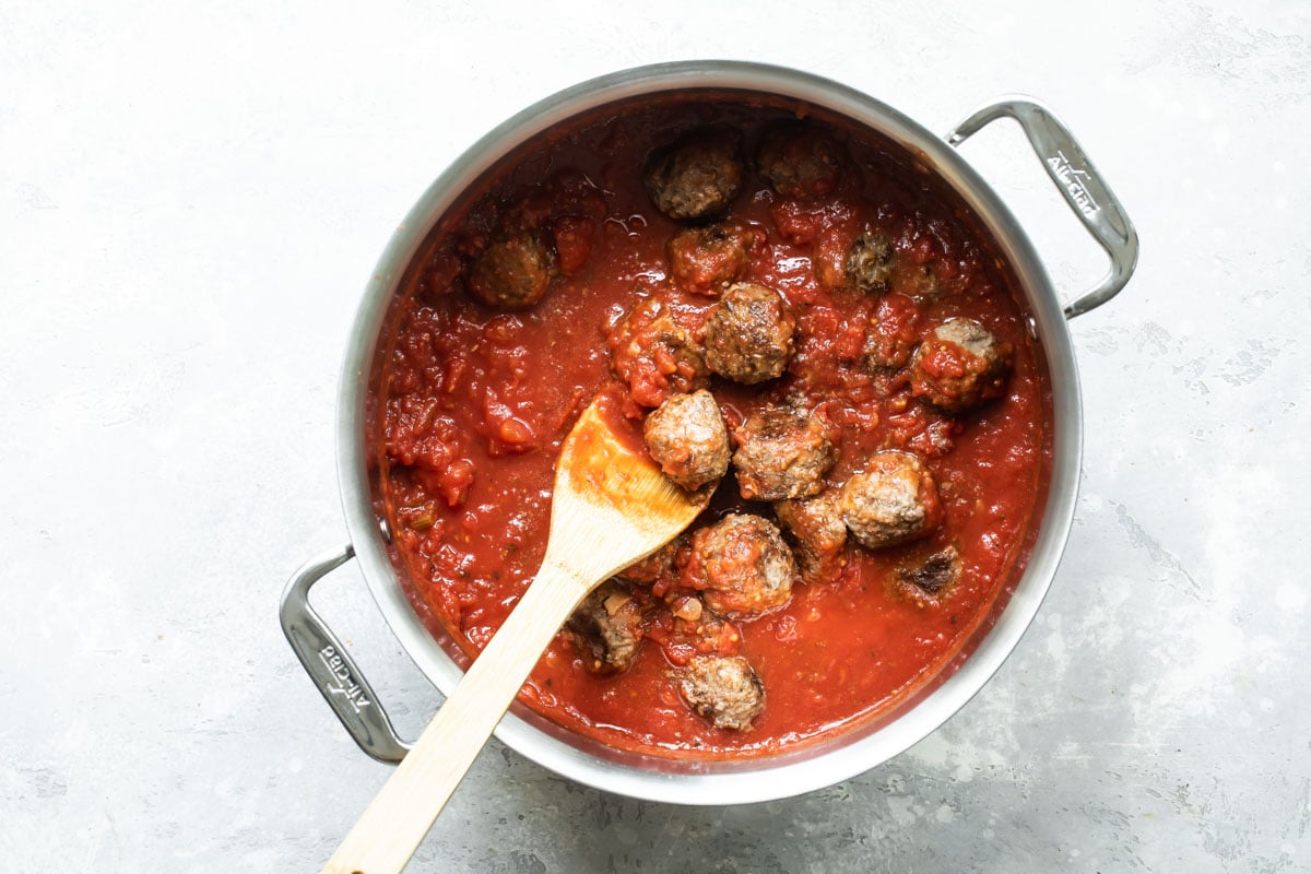 Meatballs and red sauce in a stock pot.