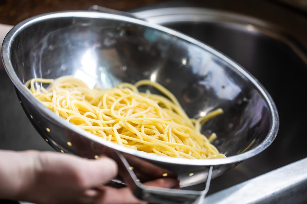 Cooked spaghetti noodles in a colander.