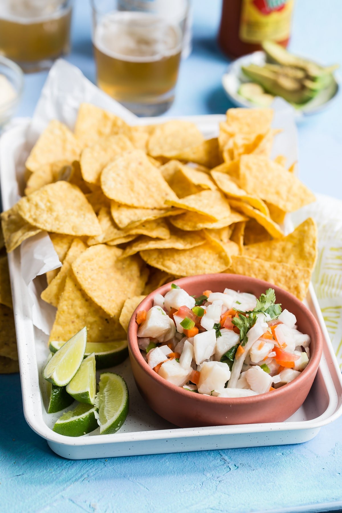 Taliapa ceviche in a pink bowl on a white platter with tortilla chips.