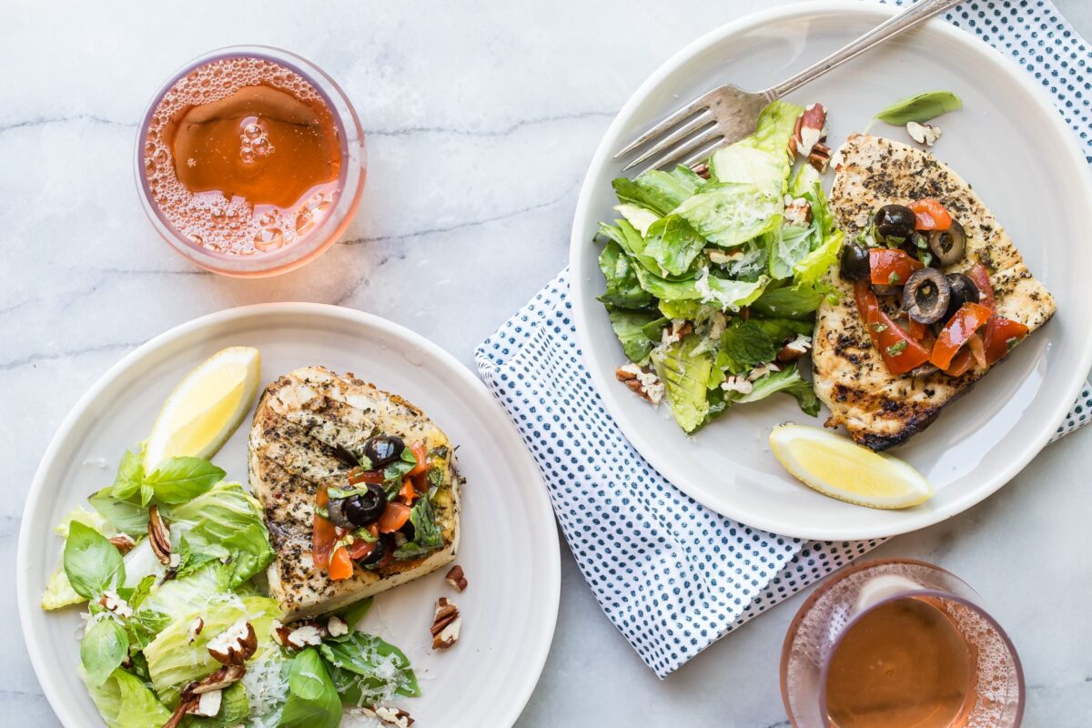 Two plates with grilled swordfish on them.