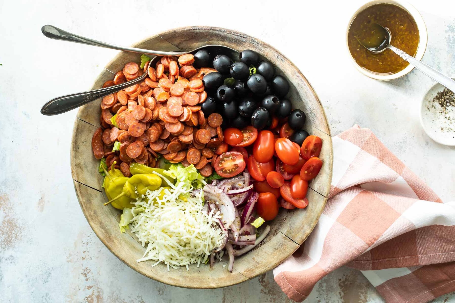 Antipasto salad ingredients in a wooden bowl.