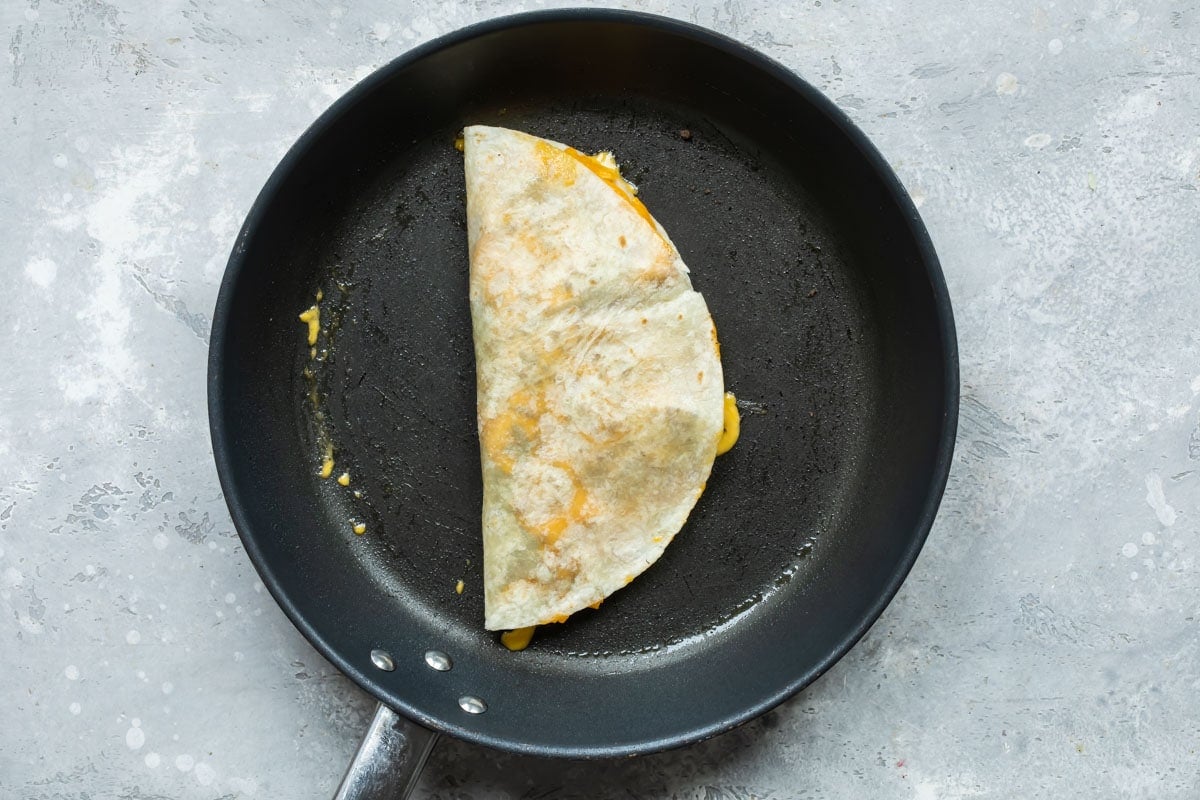 A cheesburger quesadilla in a skillet.