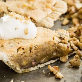 Chocolate walnut pie cut into slices on a black platter.