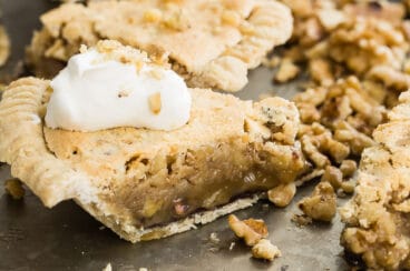 Chocolate walnut pie cut into slices on a black platter.
