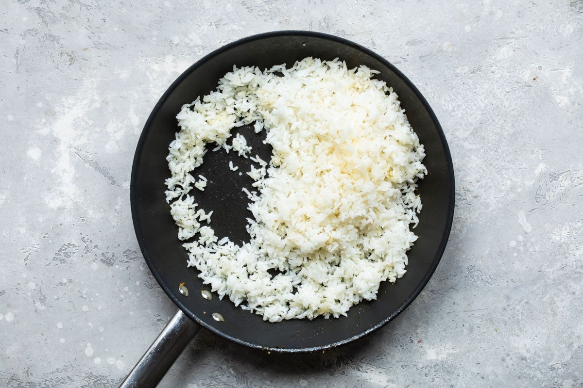 Cooked rice being fried in a skillet.