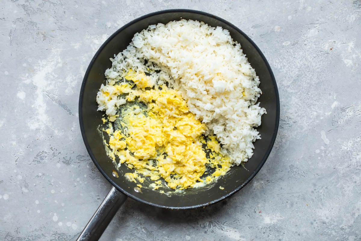 Cooked rice and eggs being cooked in a skillet.