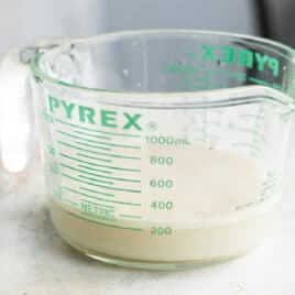 A glass measuring cup with yeast activating in warm water.