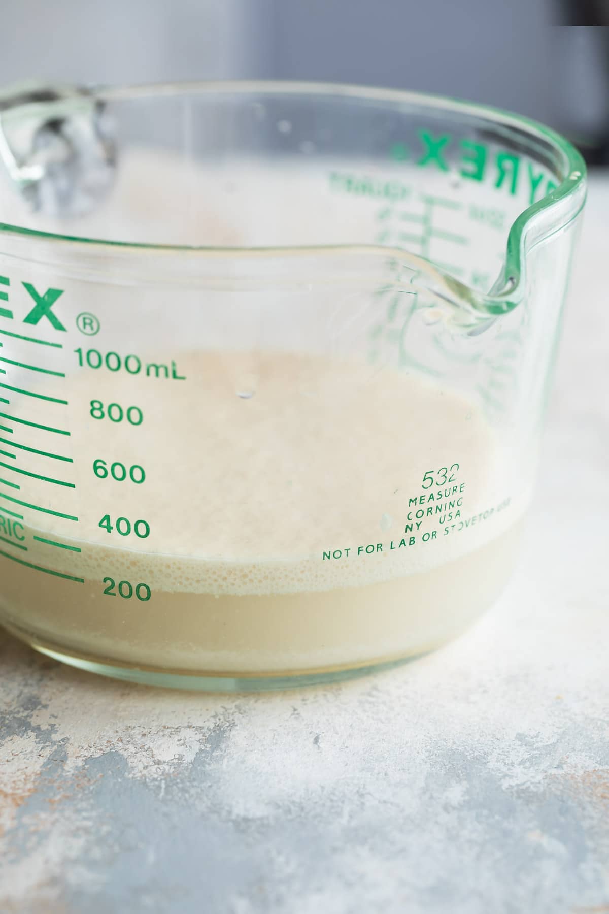 A glass measuring cup with yeast activating in warm water.