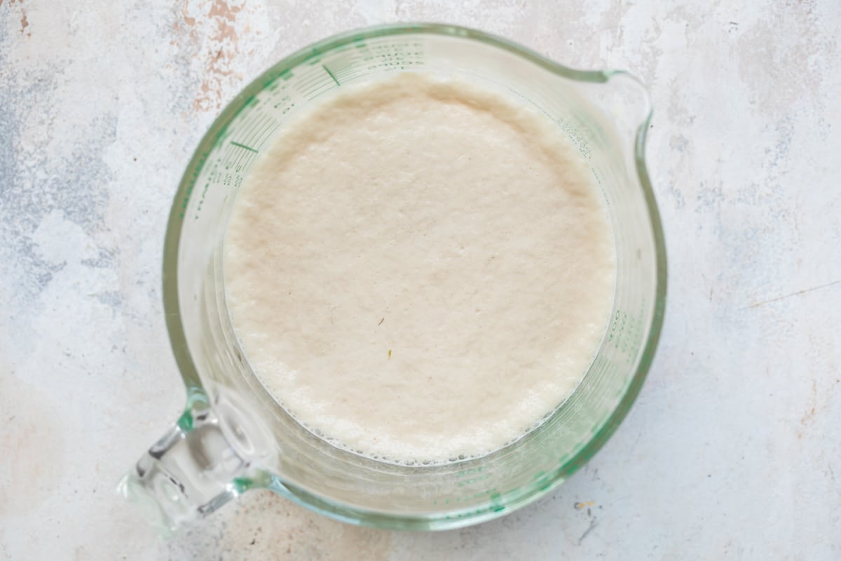 A glass measuring cup with yeast activating in warm water.