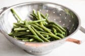 Green beans in a sliver colander.