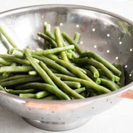 Green beans in a sliver colander.