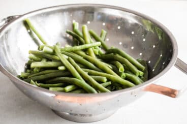 Green beans in a sliver colander.