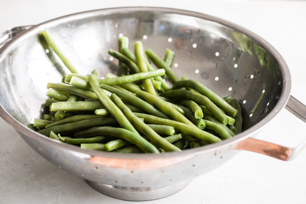Green beans in a sliver colander.