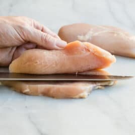 Somebody butterflying a chicken breast.