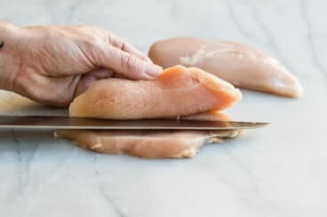 Somebody butterflying a chicken breast.