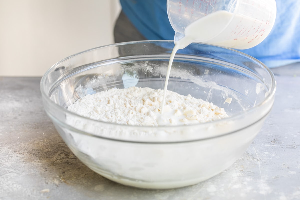 Pouring heavy cream into biscuit dough.