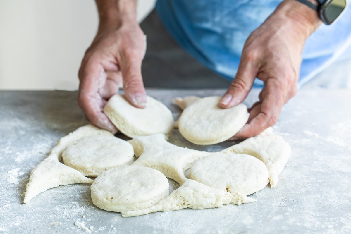 Lifting raw biscuits out of rolled out biscuit dough.