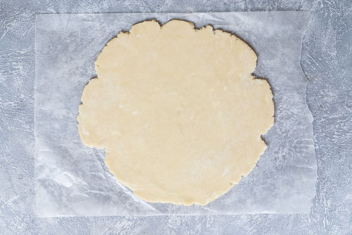 A pie crust rolled out on parchment paper.