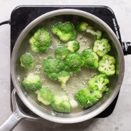 Broccoli cooking in boiling water in a silver pot.