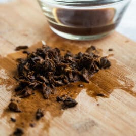 Dried mushrooms that have been rehydrated, minced on a cutting board.