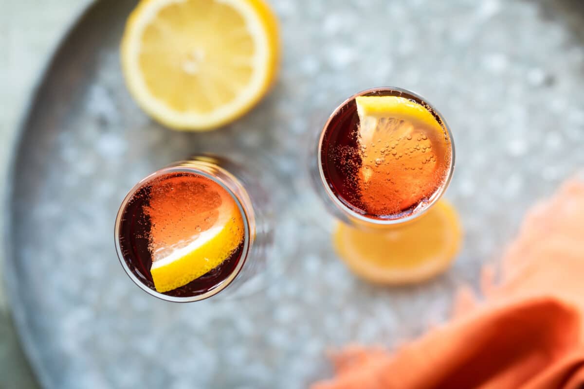 Two Kir Royale cocktails in champagne flutes on a metal tray.