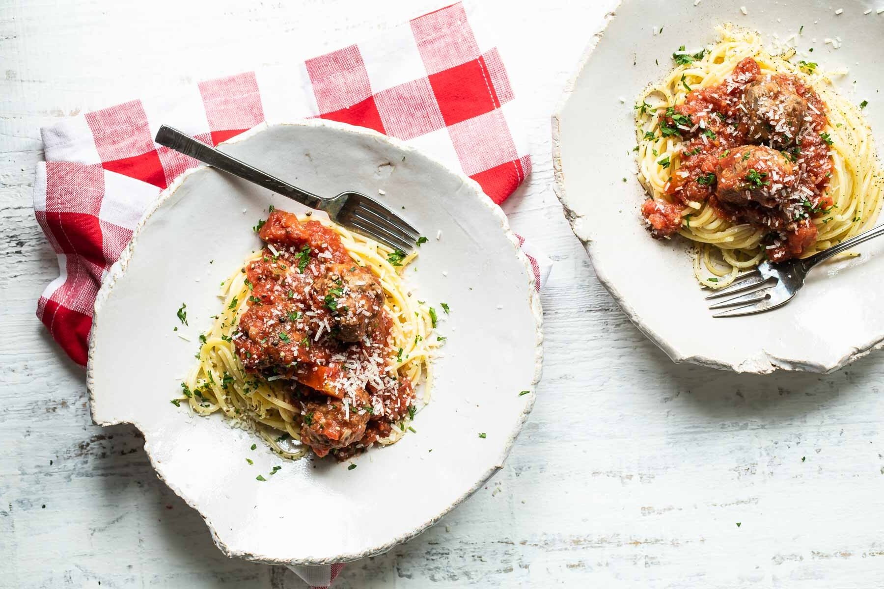 Two plates of spaghetti and meatballs.
