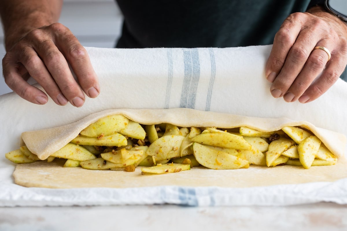Filling an apple strudel and closing the dough.