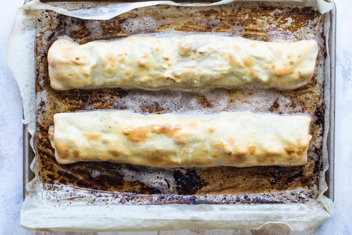 Two apple strudels on a baking sheet.
