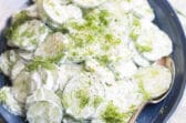 Creamy cucumber salad on a blue plate.