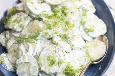 Creamy cucumber salad on a blue plate.