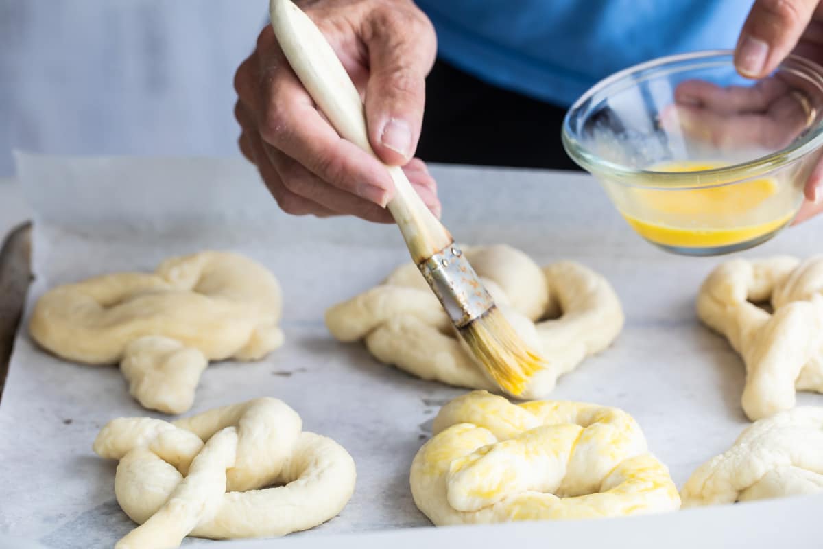 Brushing soft pretzels with egg wash.