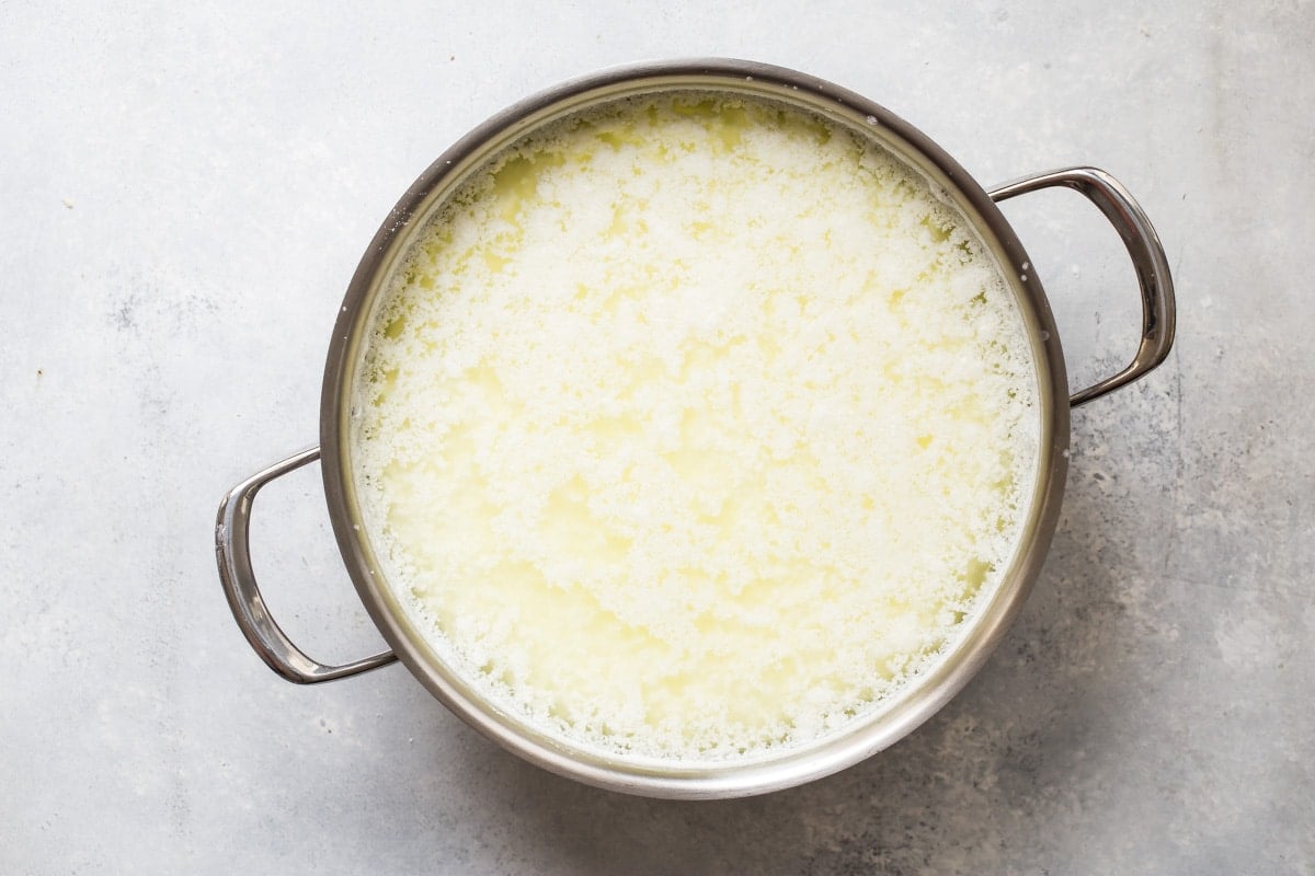 Ricotta cheese being made in a silver pan.