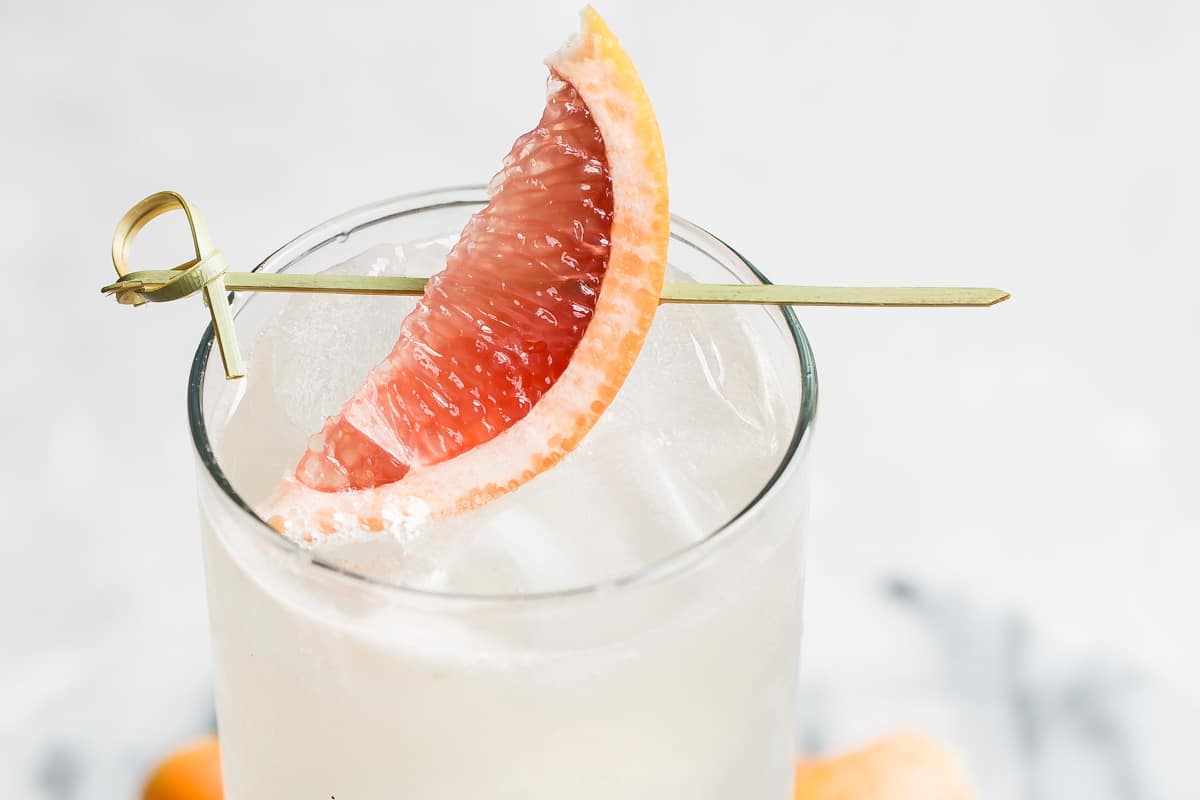 A collins glass with a Paloma cocktail in it, garnished with a grapefruit wedge.