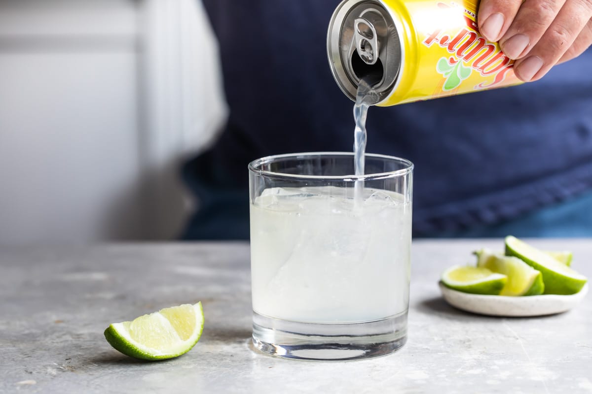 Pouring soda into a paloma cocktail.
