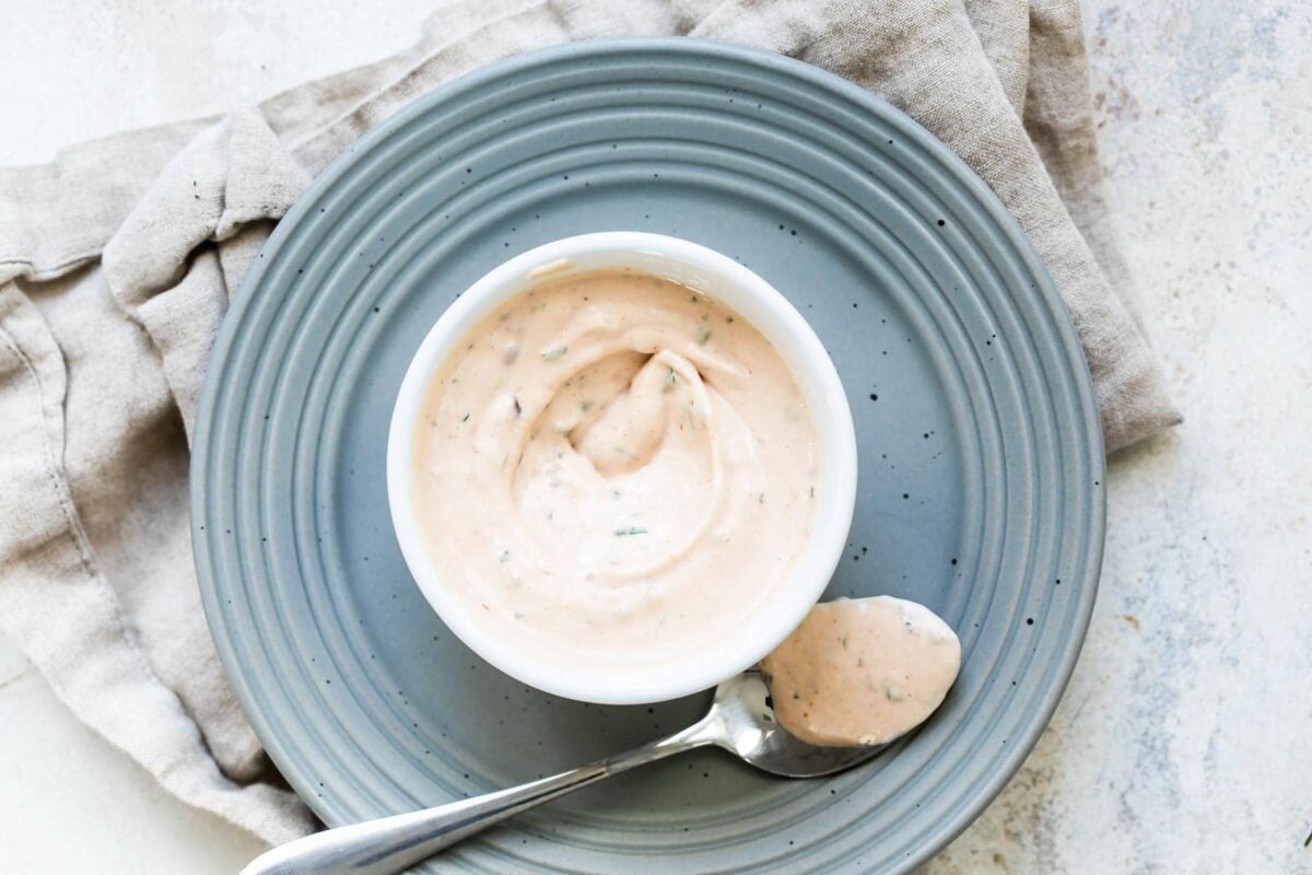 A bowl of remoulade sauce with a spoon next to it.