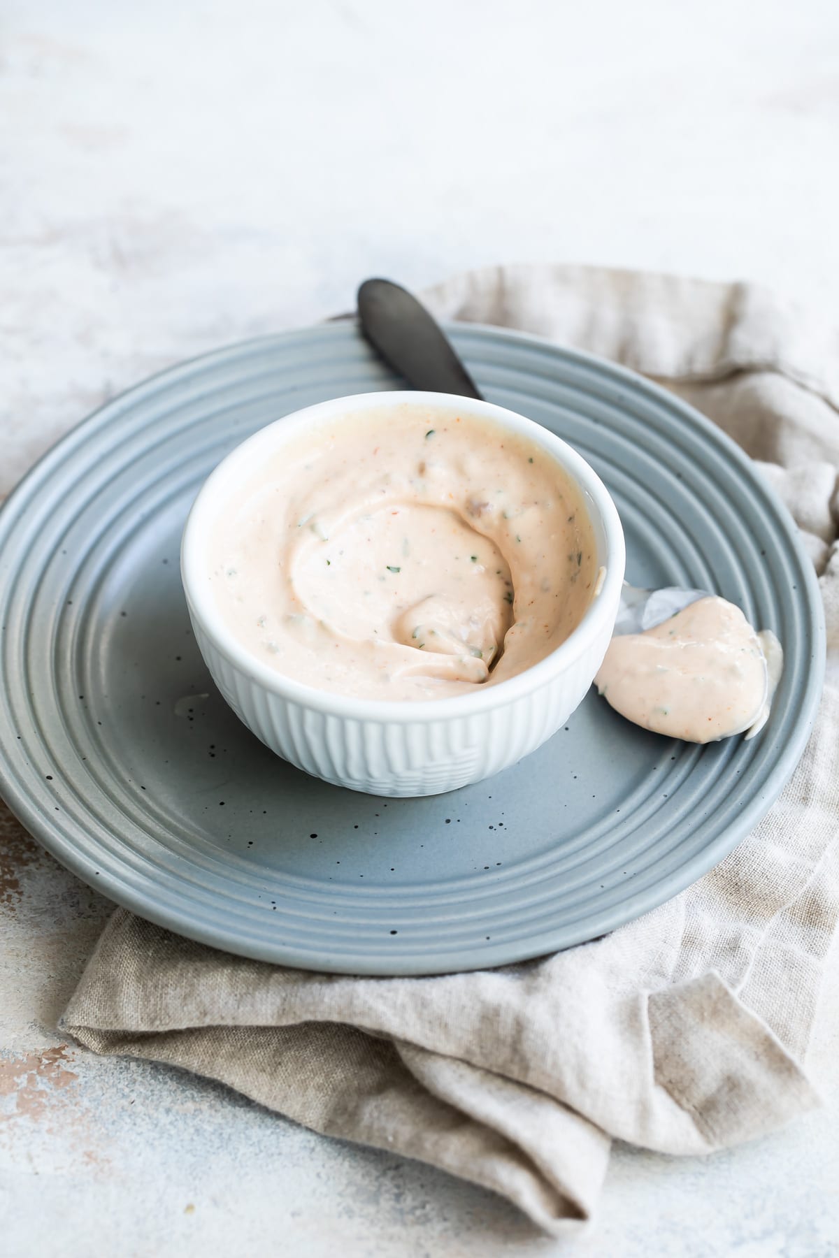 A bowl of remoulade sauce with a spoon next to it.