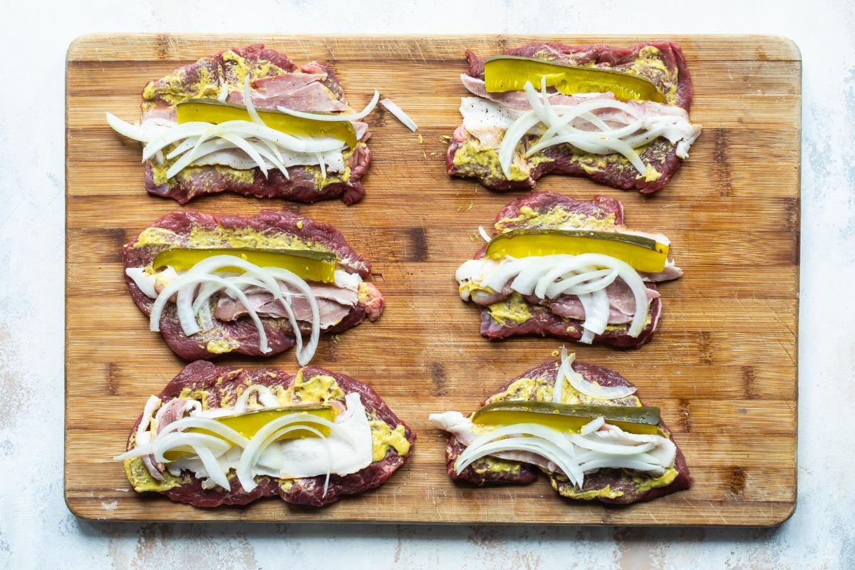 Meat layered with onions, pickles, and sauce to make rouladen.