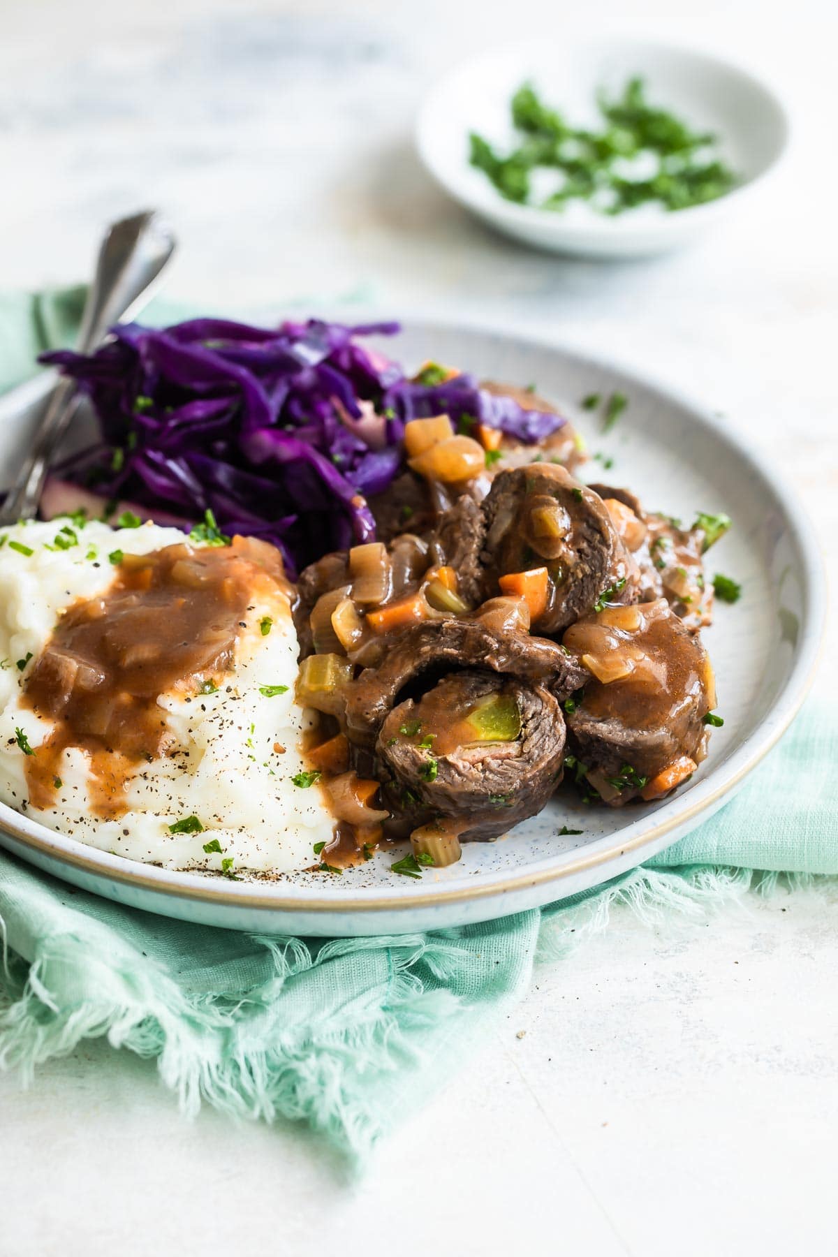 A plate with rouladen, braised red cabbage, and mashed potatoes.