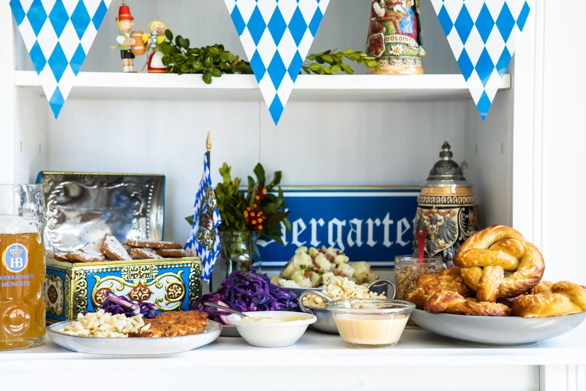 A table of Oktoberfest food including schnitzel, spaetzle, soft pretzels, German potato salad, Lebkuchen, and beer.