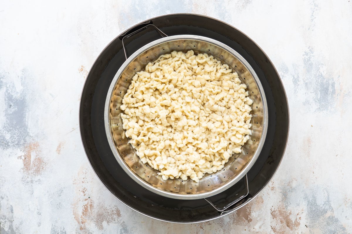 Draining boiled spaetzle in a colander.