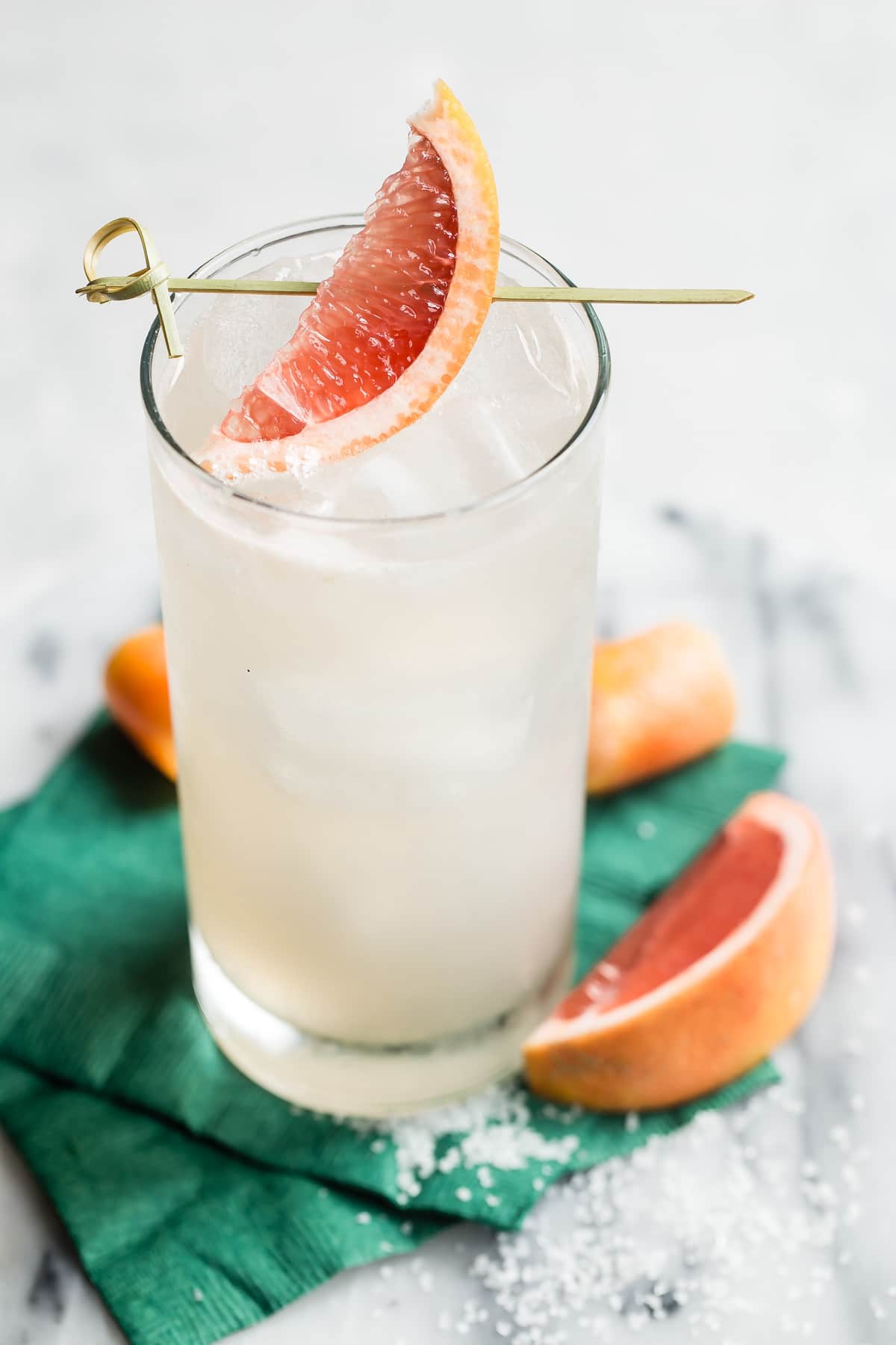 A collins glass with a Paloma cocktail in it, garnished with a grapefruit wedge.