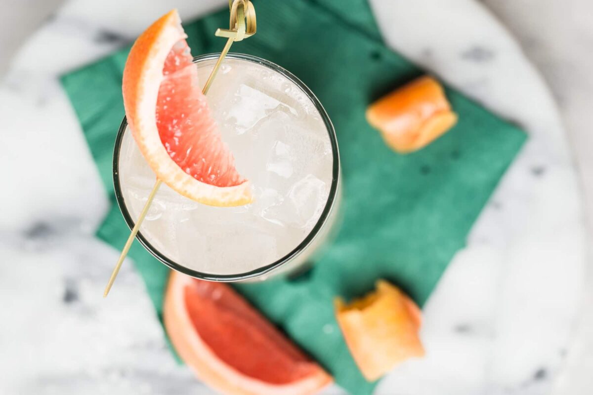 A collins glass with a Paloma cocktail in it, garnished with a grapefruit wedge.