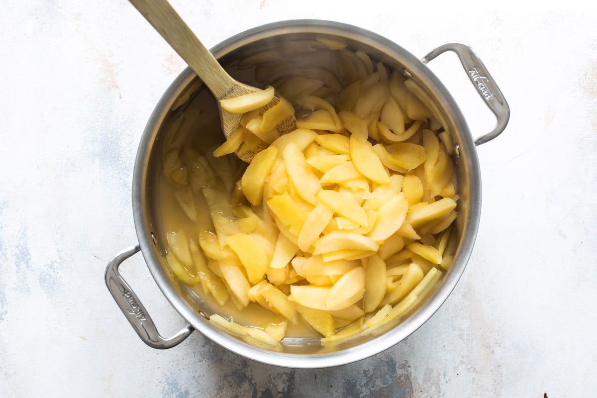 Apples being cooked in a stockpot.
