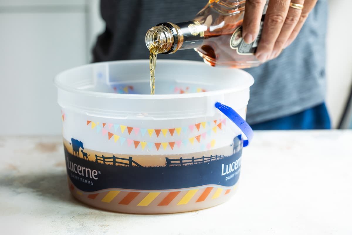 Someone pouring brandy into an ice cream pail.
