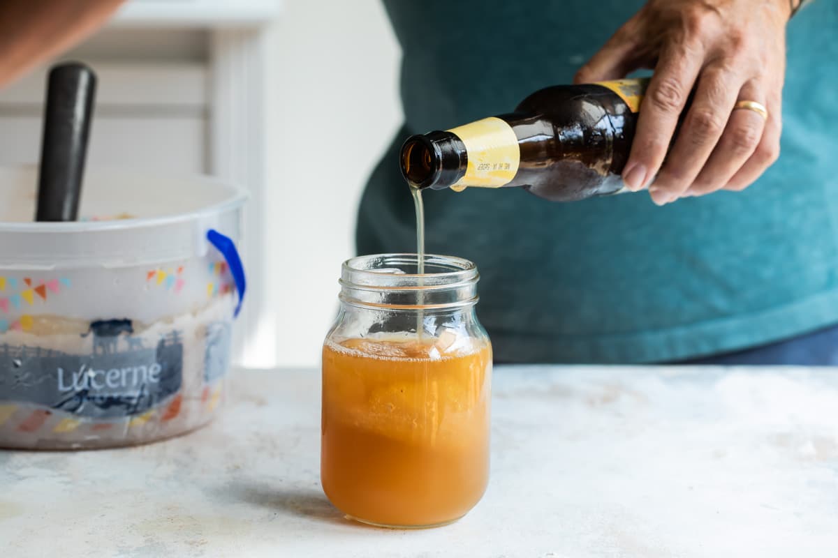 Someone pouring hard apple cider over brandy apple cider slush.
