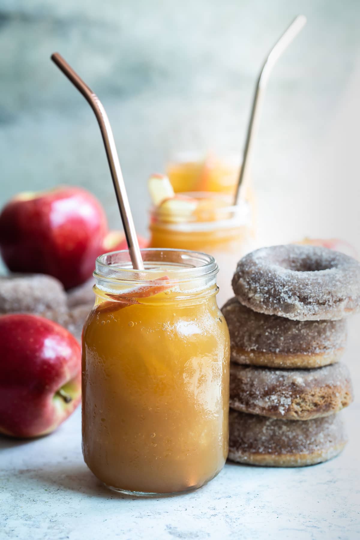 Brandy apple cider slush in a mason jar next to a stack of four brown donuts.