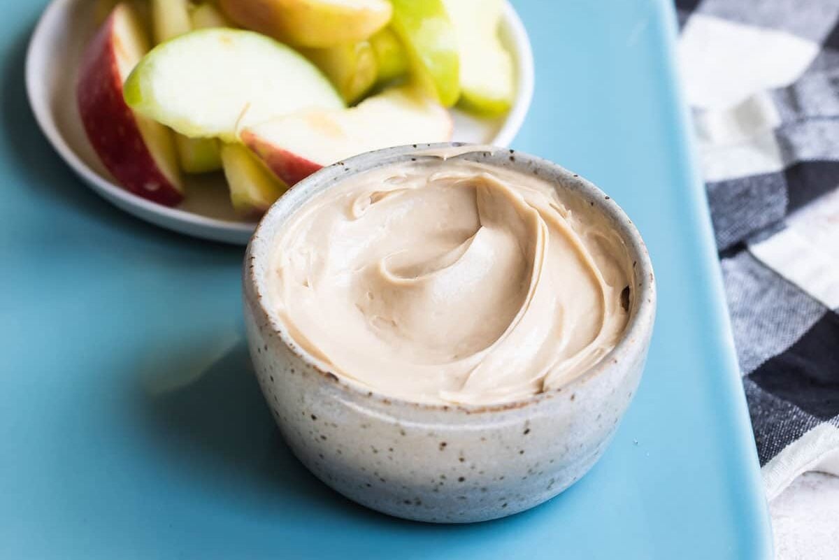 Caramel apple dip and apples on a teal platter.