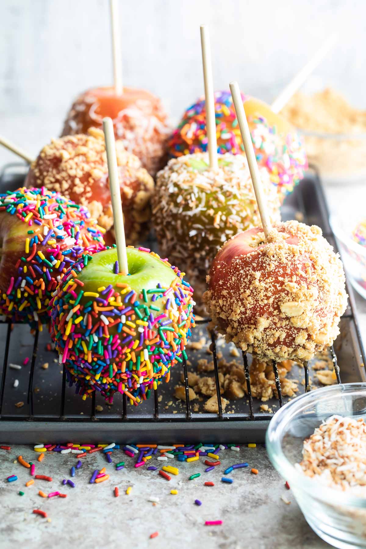 Decorated caramel apples on a cooling rack.